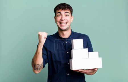 Téléchargez les photos : Homme adulte se sentant choqué, rire et célébrer le succès avec des emballages de produits vierges - en image libre de droit