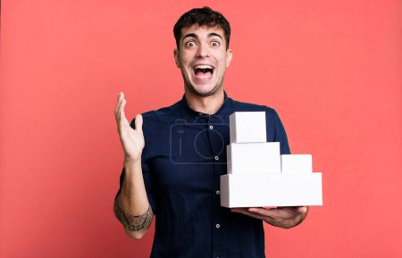 Téléchargez les photos : Homme adulte se sentant heureux et étonné de quelque chose d'incroyable avec des emballages de produits vierges - en image libre de droit