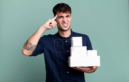 Foto de Hombre adulto sintiéndose confundido y perplejo, mostrando que está loco con paquetes de productos en blanco - Imagen libre de derechos