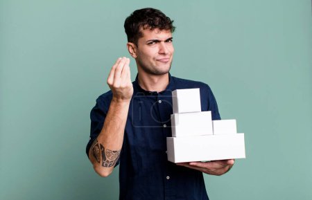 Foto de Hombre adulto haciendo capice o gesto de dinero, diciéndole que pague con paquetes de productos en blanco - Imagen libre de derechos
