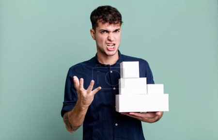 Photo for Adult man looking angry, annoyed and frustrated with blank products packages - Royalty Free Image