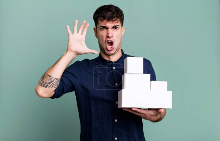 Téléchargez les photos : Homme adulte criant avec les mains en l'air avec des emballages de produits vierges - en image libre de droit