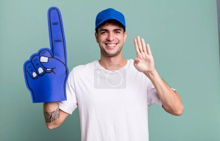 Foto de Hombre adulto sonriendo y buscando amigable, mostrando el número cuatro. concepto de ventilador número uno - Imagen libre de derechos