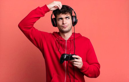 Photo for Adult man smiling happily and daydreaming or doubting with headset and a controller. gamer concept - Royalty Free Image