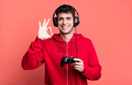 Foto de Hombre adulto sentirse feliz, mostrando aprobación con gesto bien con auriculares y un controlador. concepto de jugador - Imagen libre de derechos