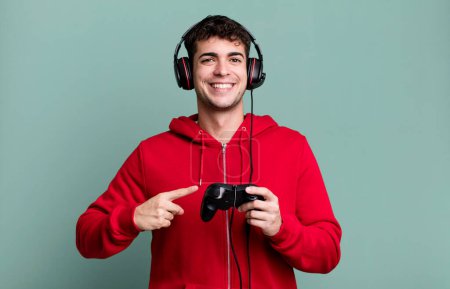 Foto de Hombre adulto mirando emocionado y sorprendido señalando a un lado con auriculares y un controlador. concepto de jugador - Imagen libre de derechos