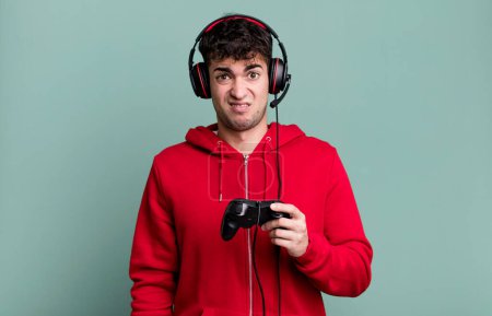 Foto de Hombre adulto sintiéndose desconcertado y confundido con auriculares y un controlador. concepto de jugador - Imagen libre de derechos