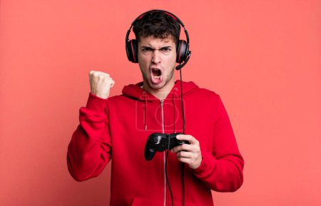 Photo for Adult man shouting aggressively with an angry expression with headset and a controller. gamer concept - Royalty Free Image