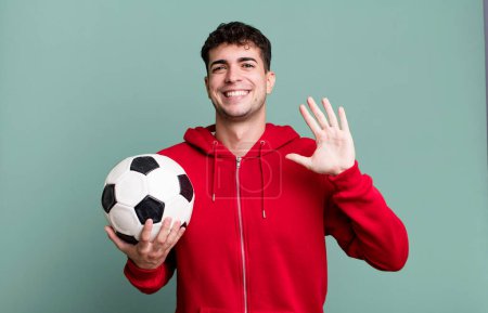Foto de Hombre adulto sonriendo felizmente, saludándote con la mano, dándote la bienvenida y saludándote. concepto de fútbol y deporte - Imagen libre de derechos