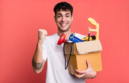 Foto de Hombre adulto se siente sorprendido, riendo y celebrando el éxito con una caja de herramientas. concepto de ama de llaves - Imagen libre de derechos