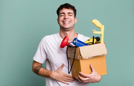 Foto de Hombre adulto riendo en voz alta en alguna broma hilarante con una caja de herramientas. concepto de ama de llaves - Imagen libre de derechos