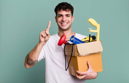 Photo for Adult man smiling and looking friendly, showing number one with a toolbox. housekeeper concept - Royalty Free Image