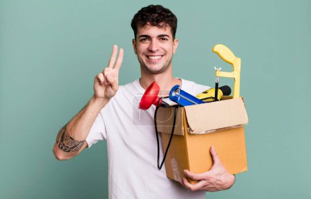 Photo for Adult man smiling and looking friendly, showing number two with a toolbox. housekeeper concept - Royalty Free Image