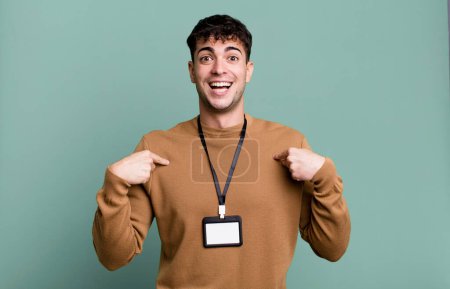 Foto de Hombre adulto sintiéndose feliz y señalándose a sí mismo con un excitado con una tarjeta de identidad de acceso - Imagen libre de derechos