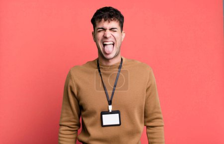 Foto de Hombre adulto con actitud alegre y rebelde, bromeando y sacando la lengua con una tarjeta de identidad de acceso - Imagen libre de derechos