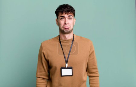 Foto de Hombre adulto sintiéndose triste y quejumbroso con una mirada infeliz y llorando con una tarjeta de identidad de acceso - Imagen libre de derechos