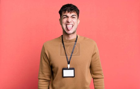 Téléchargez les photos : Homme adulte se sentant dégoûté et irrité et la langue avec une carte d'identité d'accès - en image libre de droit