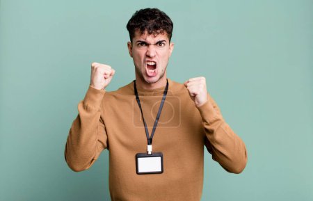 Foto de Hombre adulto gritando agresivamente con una expresión enojada con una tarjeta de identidad de acceso - Imagen libre de derechos