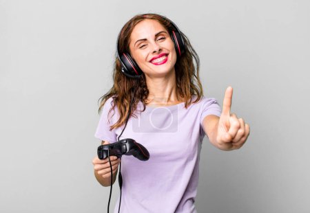 Photo for Hispanic pretty woman smiling and looking friendly, showing number one. gamer concept - Royalty Free Image