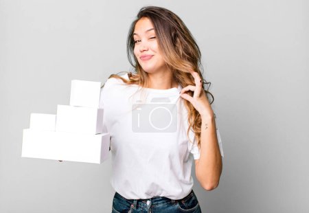 Photo for Hispanic pretty woman looking arrogant, successful, positive and proud with white boxes packages - Royalty Free Image