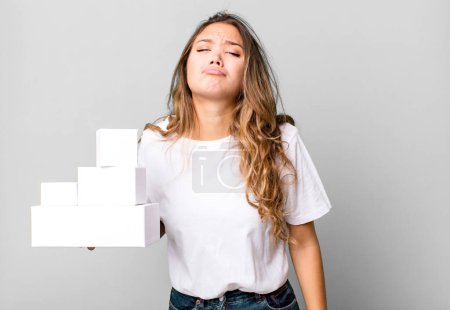 Photo for Hispanic pretty woman feeling sad and whiney with an unhappy look and crying with white boxes packages - Royalty Free Image