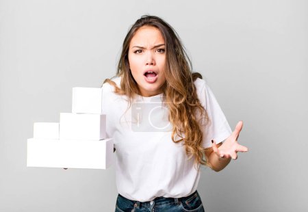 Photo for Hispanic pretty woman looking angry, annoyed and frustrated with white boxes packages - Royalty Free Image