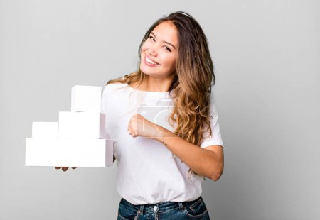 Photo for Hispanic pretty woman feeling happy and facing a challenge or celebrating with white boxes packages - Royalty Free Image