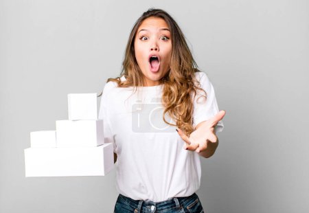 Photo for Hispanic pretty woman feeling extremely shocked and surprised with white boxes packages - Royalty Free Image