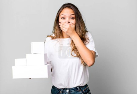 Photo for Hispanic pretty woman covering mouth with hands with a shocked with white boxes packages - Royalty Free Image