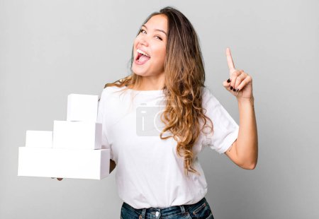 Photo for Hispanic pretty woman feeling like a happy and excited genius after realizing an idea with white boxes packages - Royalty Free Image