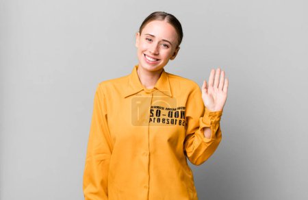 Photo for Caucasian pretty woman smiling happily, waving hand, welcoming and greeting you. guilt concept - Royalty Free Image