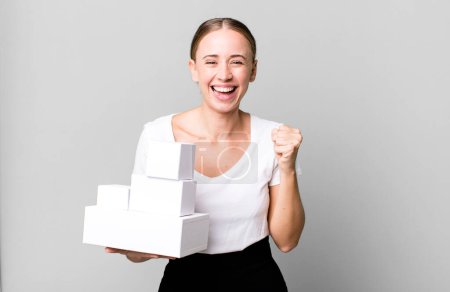 Foto de Caucasian pretty woman feeling shocked,laughing and celebrating success with white boxes packages - Imagen libre de derechos