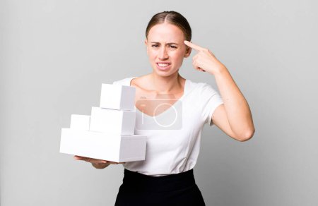 Photo for Caucasian pretty woman feeling confused and puzzled, showing you are insane with white boxes packages - Royalty Free Image