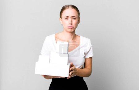 Photo for Caucasian pretty woman feeling sad and whiney with an unhappy look and crying with white boxes packages - Royalty Free Image