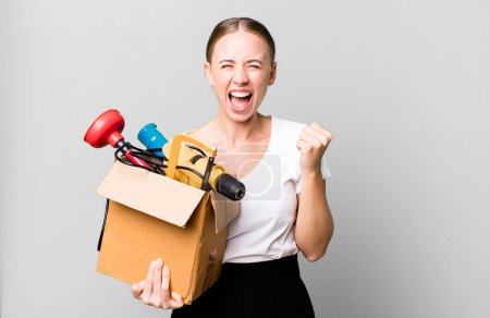 Foto de Caucasian pretty woman shouting aggressively with an angry expression with a tool box. repair home concept - Imagen libre de derechos