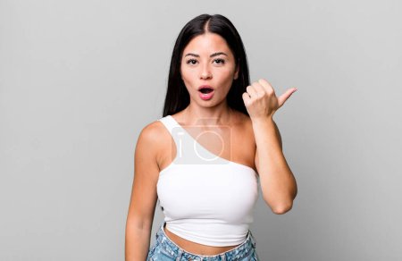 Photo for Pretty latin woman looking astonished in disbelief, pointing at object on the side and saying wow, unbelievable - Royalty Free Image