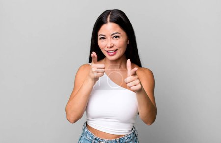 Photo for Pretty latin woman smiling with a positive, successful, happy attitude pointing to the camera, making gun sign with hands - Royalty Free Image