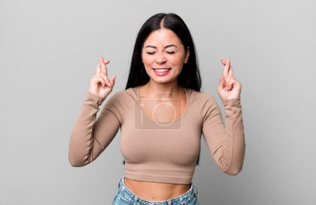 Photo for Pretty latin woman feeling nervous and hopeful, crossing fingers, praying and hoping for good luck - Royalty Free Image