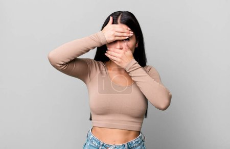 Photo for Pretty latin woman covering face with both hands saying no to the camera! refusing pictures or forbidding photos - Royalty Free Image