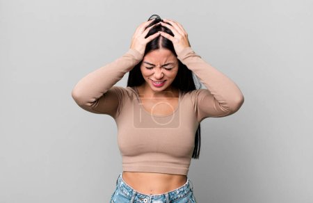 Foto de Mujer latina bonita sintiéndose estresada y frustrada, levantando las manos a la cabeza, sintiéndose cansada, infeliz y con migraña - Imagen libre de derechos