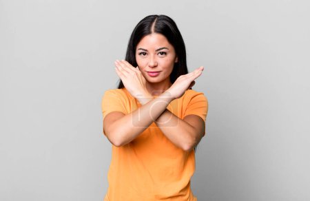 Photo for Pretty latin woman looking annoyed and sick of your attitude, saying enough! hands crossed up front, telling you to stop - Royalty Free Image