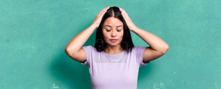Photo for Pretty latin woman looking concentrated, thoughtful and inspired, brainstorming and imagining with hands on forehead - Royalty Free Image