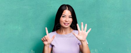 Foto de Pretty latin woman smiling and looking friendly, showing number seven or seventh with hand forward, counting down - Imagen libre de derechos