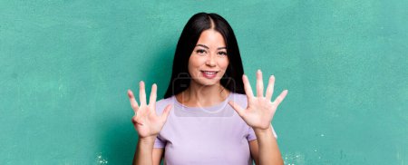 Téléchargez les photos : Jolie femme latine souriante et amicale, montrant numéro neuf ou neuvième avec la main vers l'avant, compte à rebours - en image libre de droit