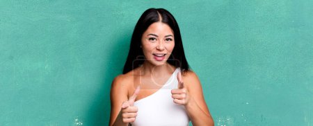 Photo for Pretty latin woman feeling happy, cool, satisfied, relaxed and successful, pointing at camera, choosing you - Royalty Free Image