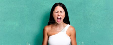 Photo for Pretty latin woman screaming furiously, shouting aggressively, looking stressed and angry - Royalty Free Image