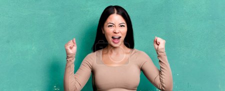 Foto de Mujer latina bonita gritando agresivamente con una expresión enojada o con los puños apretados celebrando el éxito - Imagen libre de derechos