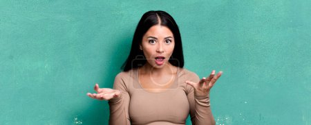 Photo for Pretty latin woman feeling extremely shocked and surprised, anxious and panicking, with a stressed and horrified look - Royalty Free Image