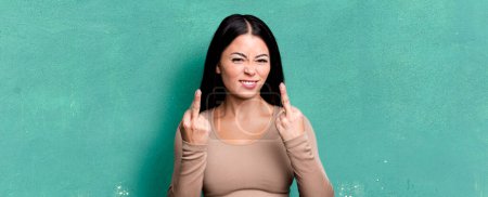 Photo for Pretty latin woman feeling provocative, aggressive and obscene, flipping the middle finger, with a rebellious attitude - Royalty Free Image