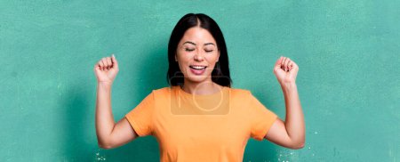 Foto de Pretty latin woman looking extremely happy and surprised, celebrating success, shouting and jumping - Imagen libre de derechos